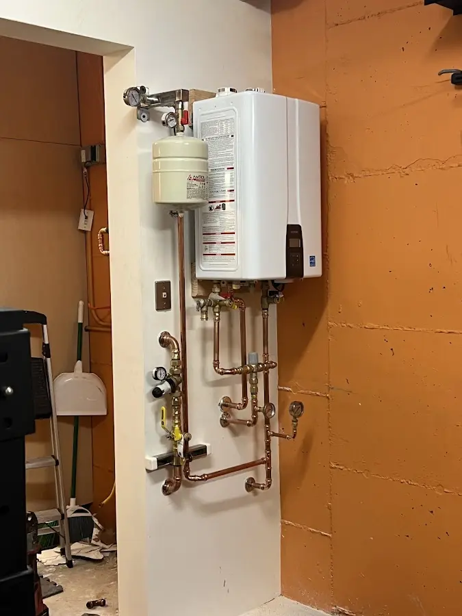Plumbing technician inspecting water heater connections in PiÃÂ±on Hills